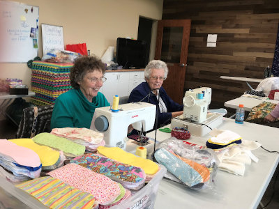 two ladies sitting in front of sewing machines